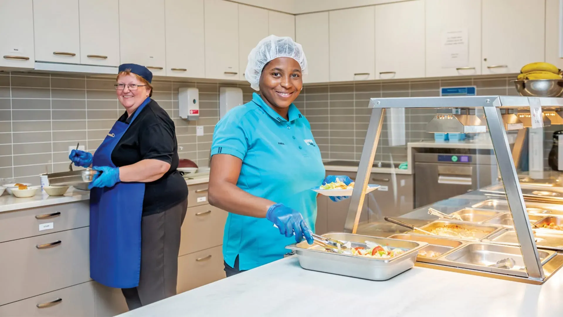 Aged care kitchen staff preparing food in a commercial coolroom.
